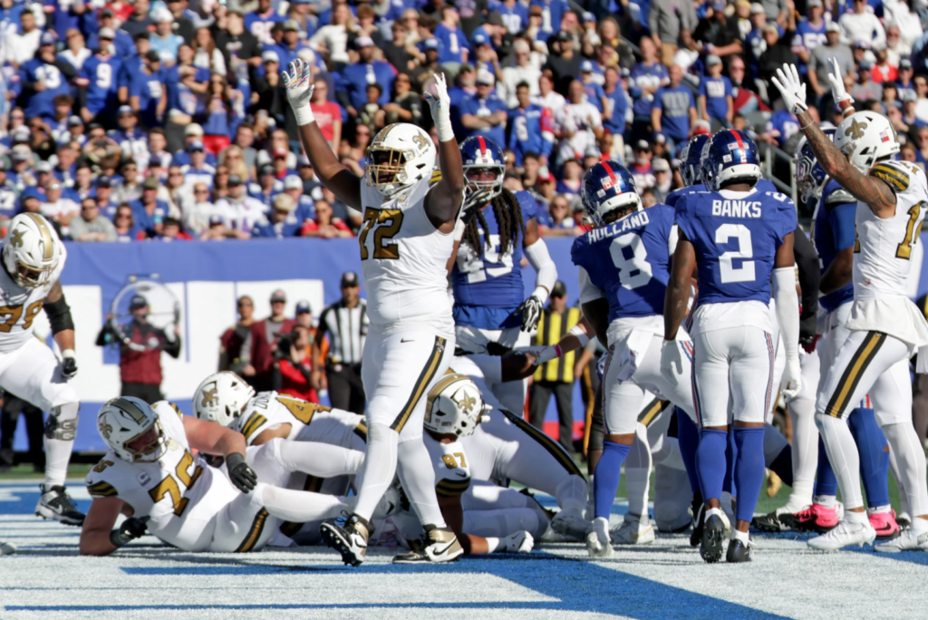 Acredite, Tyler Shough está no meio dessa pilha, anotando o seu touchdown terrestre contra os Giants (Layne Murdoch Jr. / New Orleans Saints)